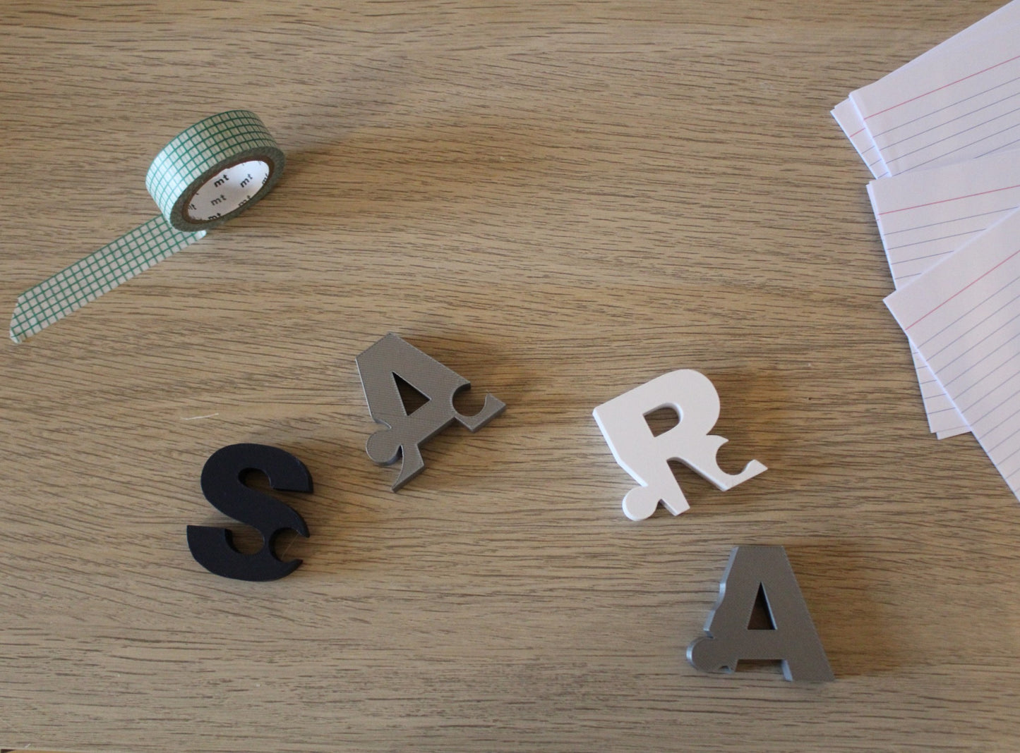 A puzzle of the name Sara is disassembled on a desk