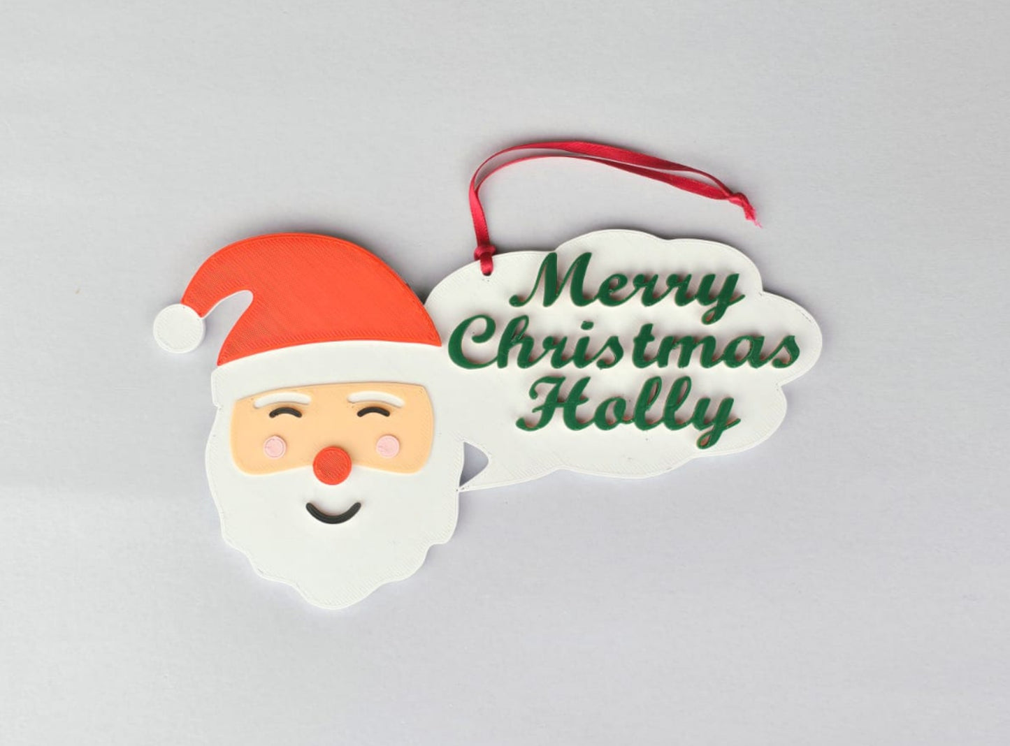 Christmas ornament with Santa face and 'Merry Christmas Holly' text on a gray background
