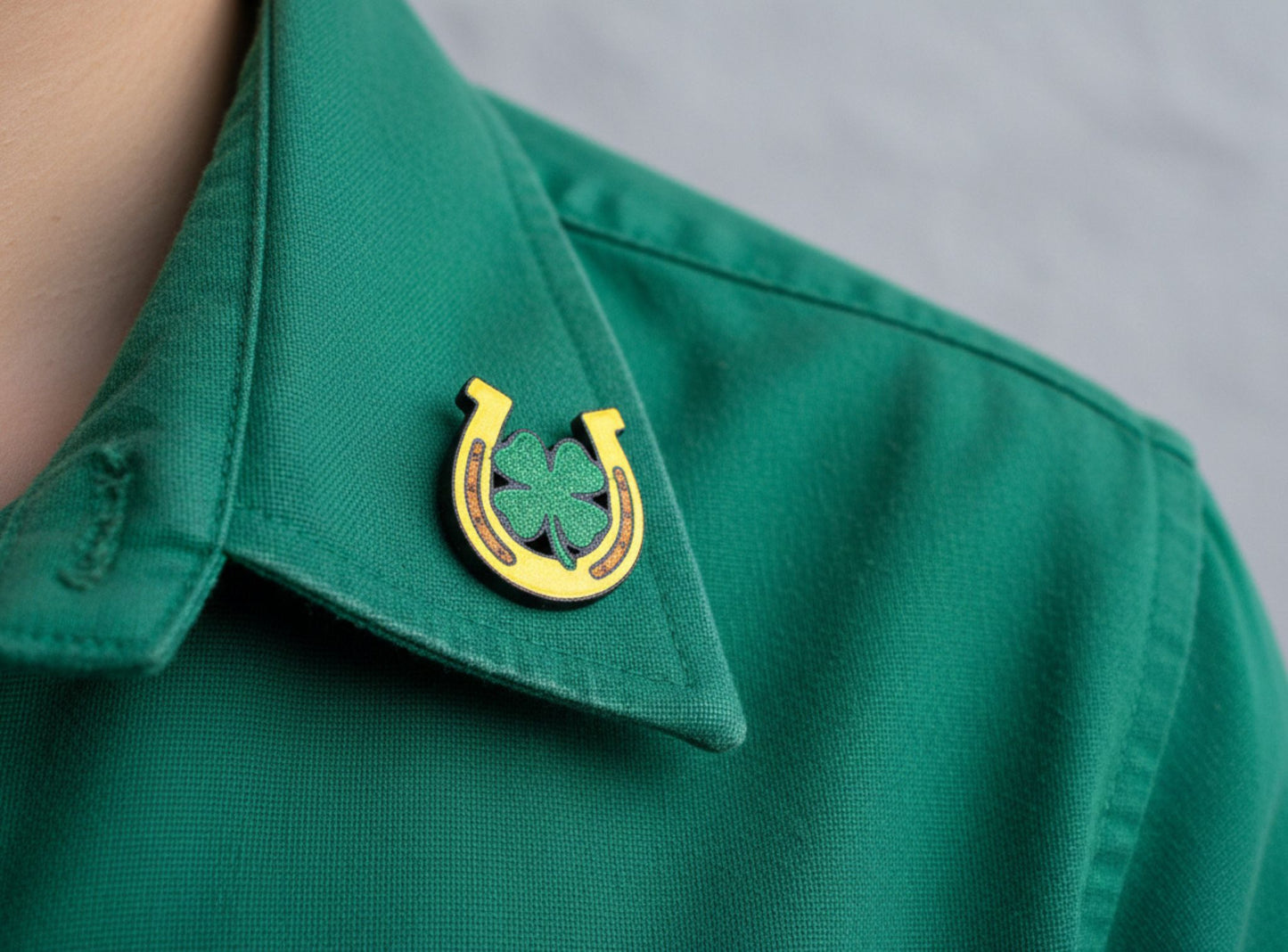 Horseshoe with a four-leaf clover on a light grey background
