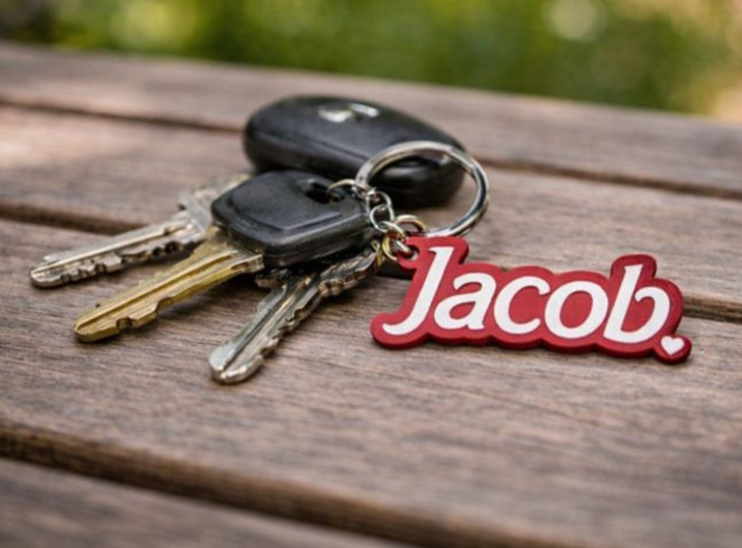 Keychain with keys and a red 'Jacob' charm on a wooden surface