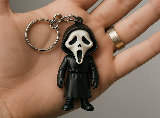 Keychain with the character Ghostface held in a hand against a gray background