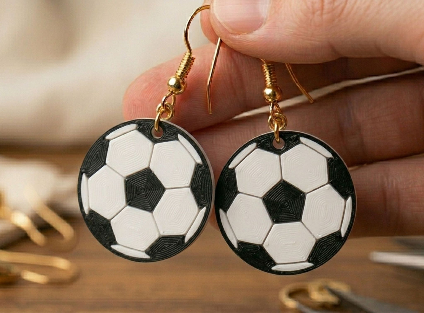 Football-shaped earrings held by a hand on a blurred background