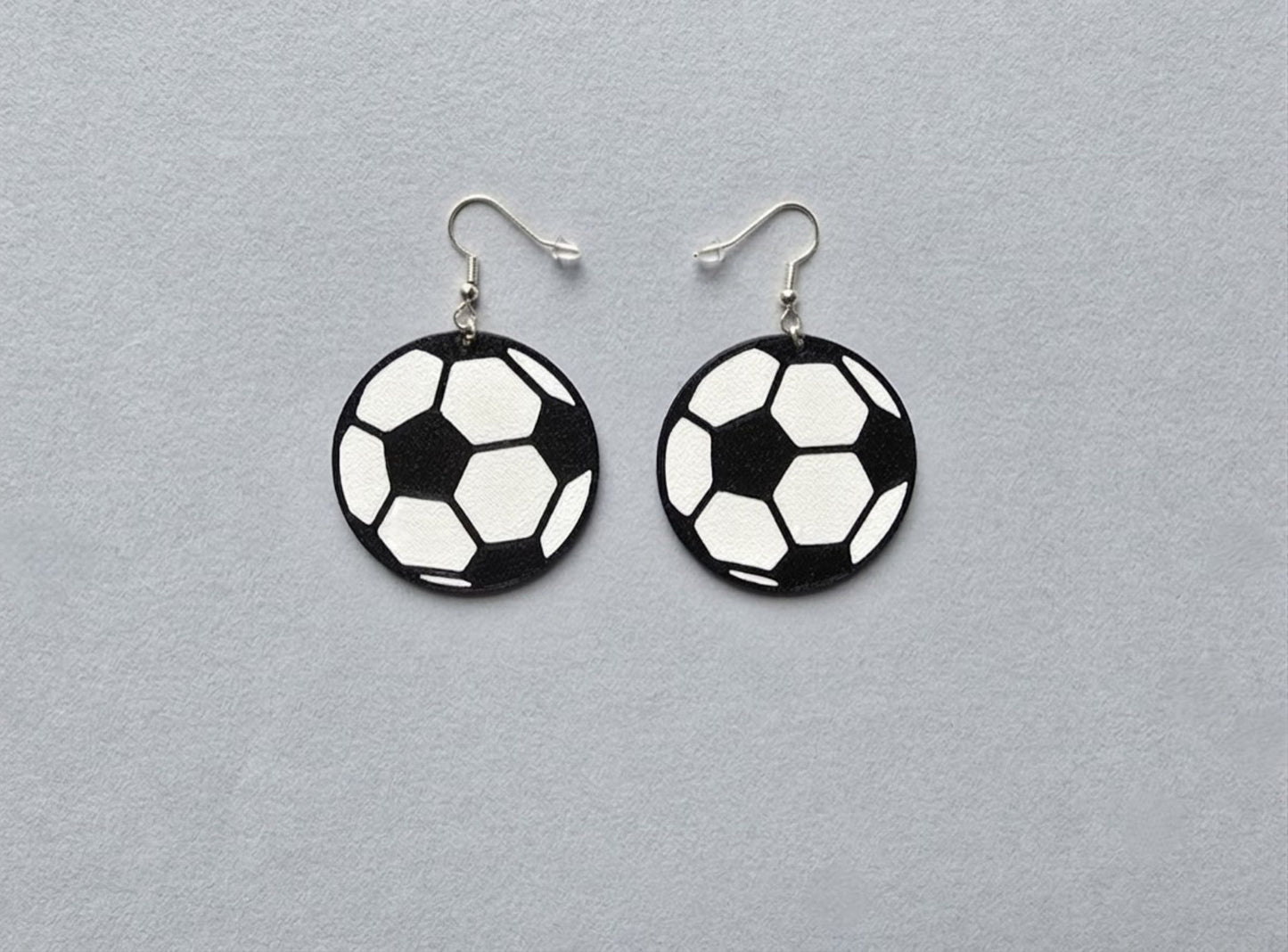 Soccer ball earrings on a gray background