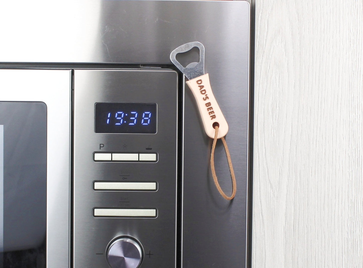 Beige Personalised Bottle Opener with the inscription DAD'S BEER in Brown, magnetized to a microwave