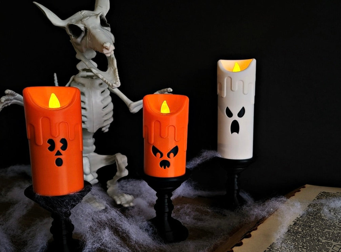 Halloween-themed LED candles with a skeleton and old book on a dark background