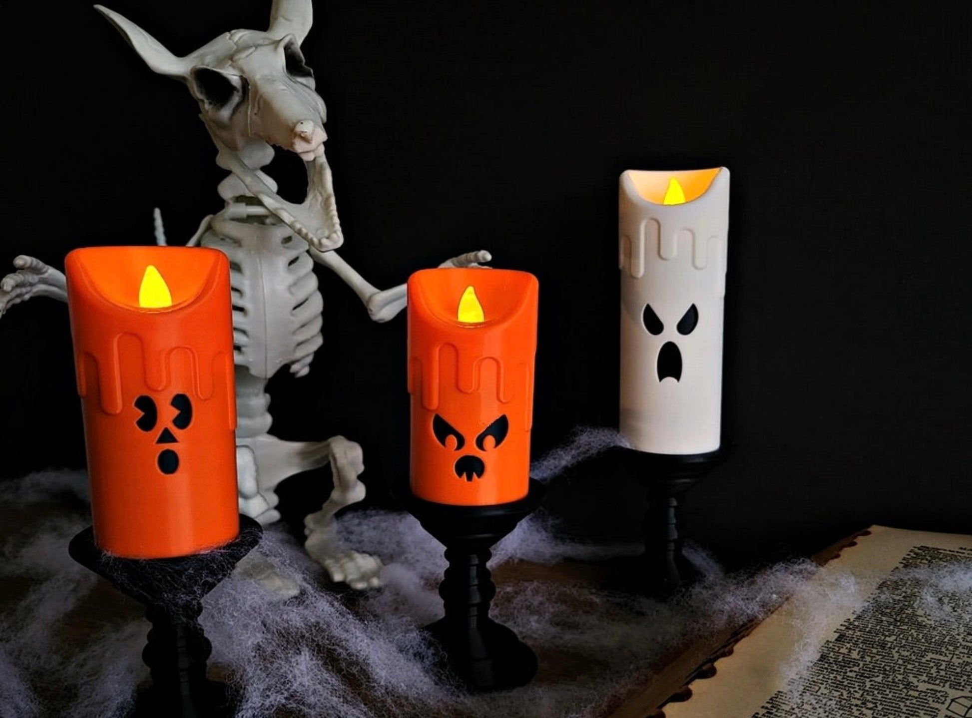Halloween-themed LED candles with a skeleton and old book on a dark background