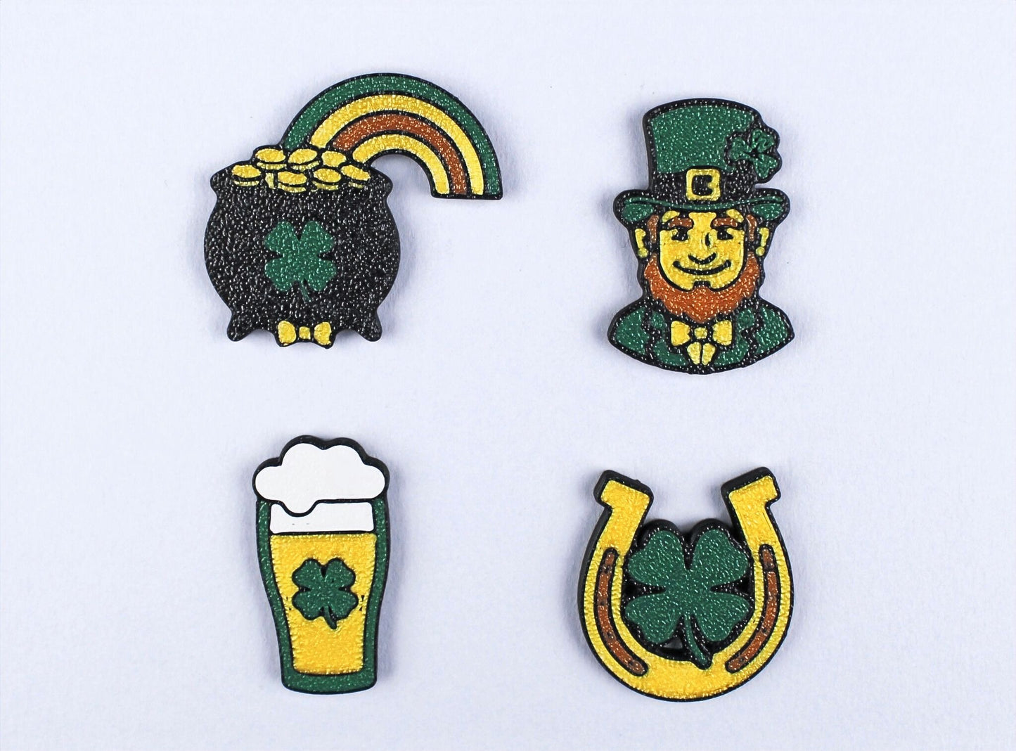 Set of four St. Patrick's Day-themed lapel pins on a light grey background.