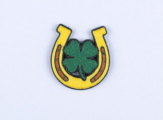 Horseshoe lapel pin with a four-leaf clover on a light grey background