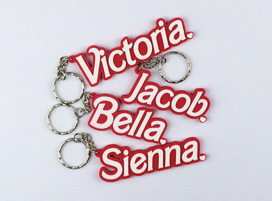 Three 3D Printed Personalised Barbie Style Name Keyring on a light gray background