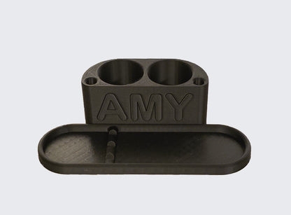 3D printed Black Personalised Makeup Brush Holder with 'AMY' branding on a light gray background