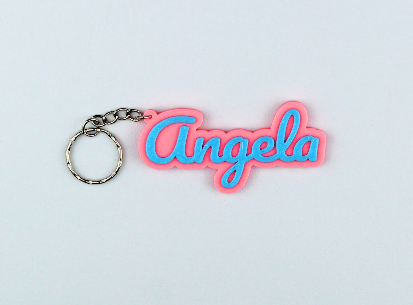 3D Printed Keychain with 'Angela' in pink and blue on a light gray background