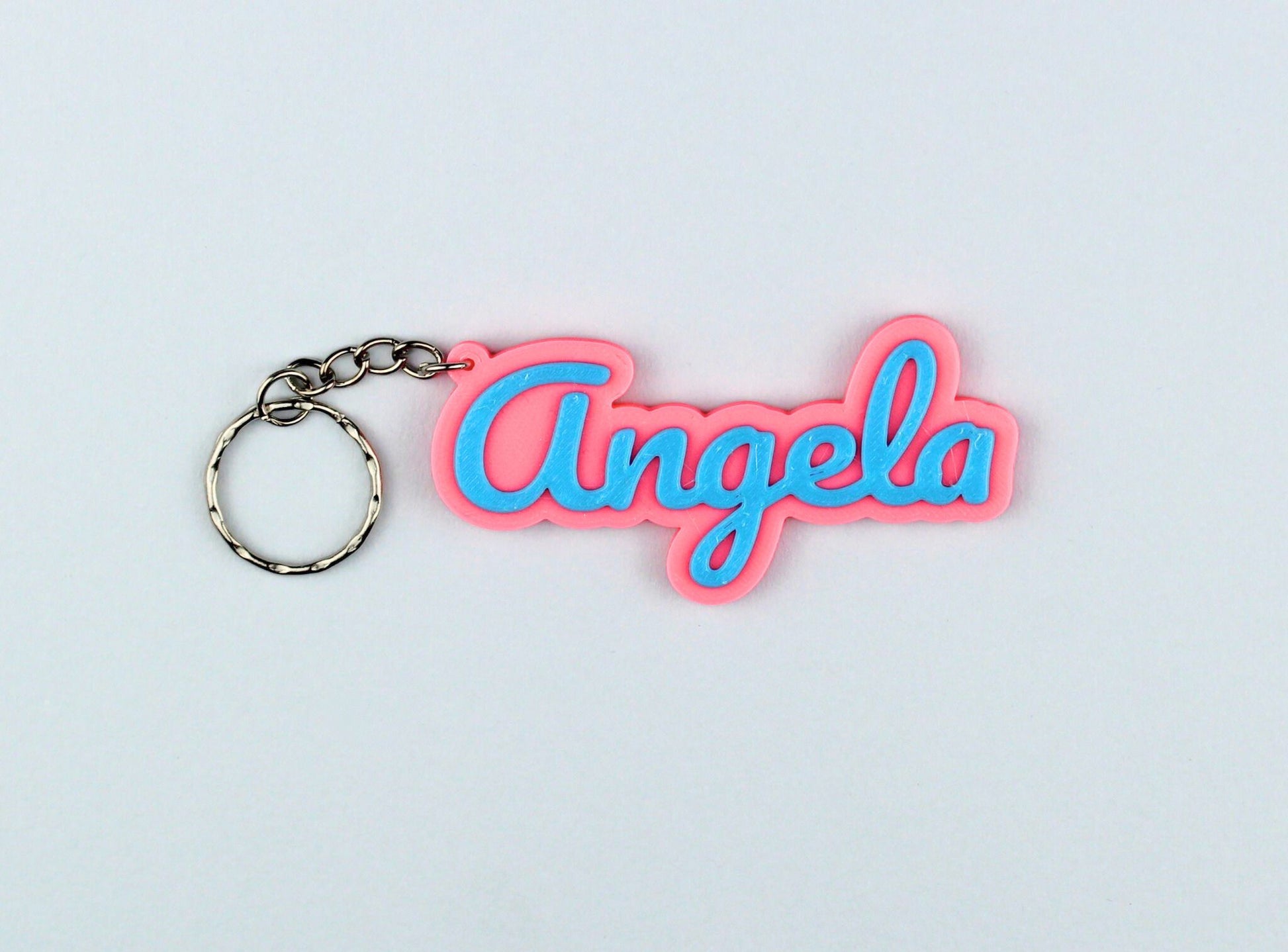 3D Printed Keychain with 'Angela' in pink and blue on a light gray background