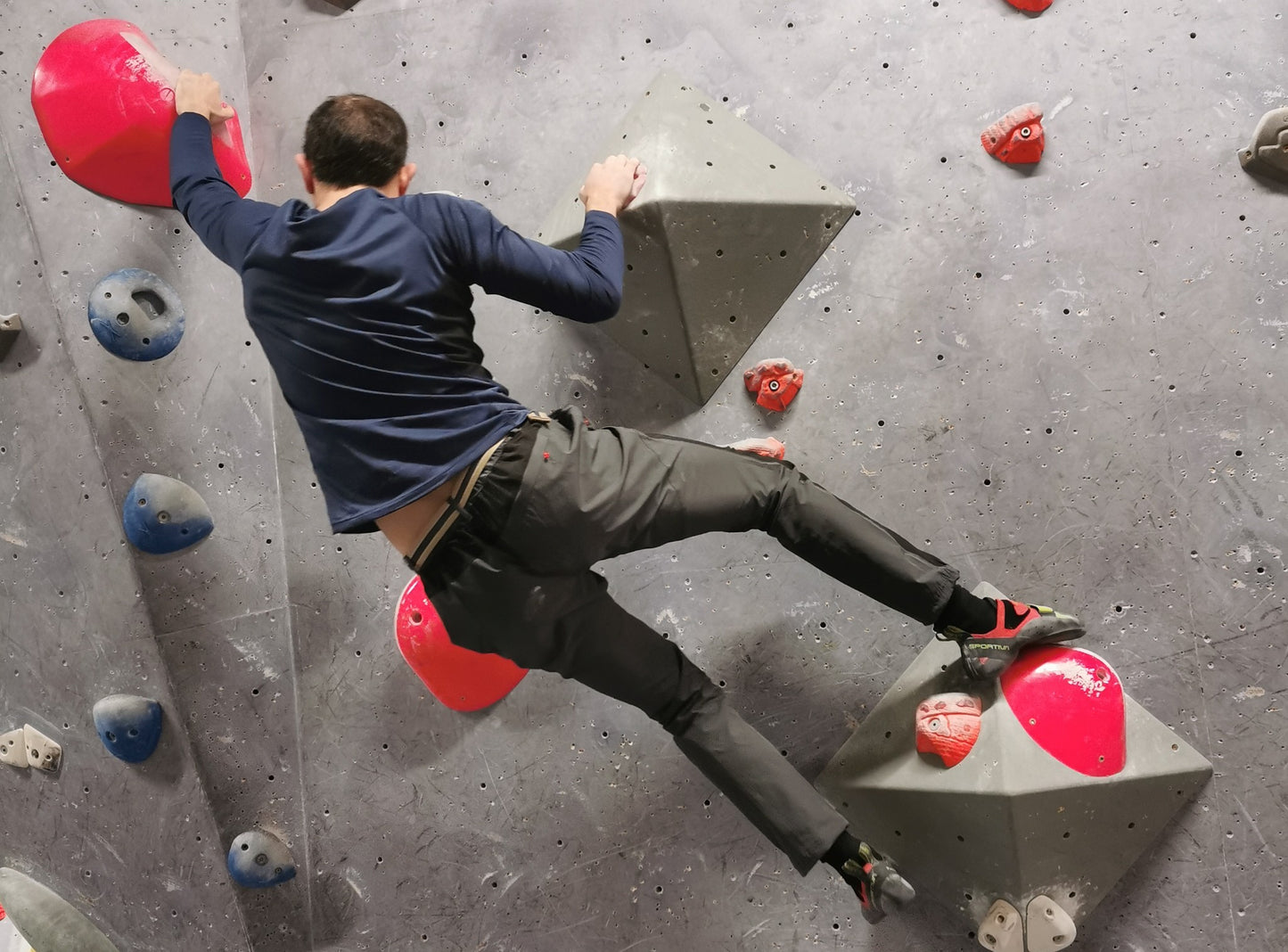 A man hanging on a climbing wall