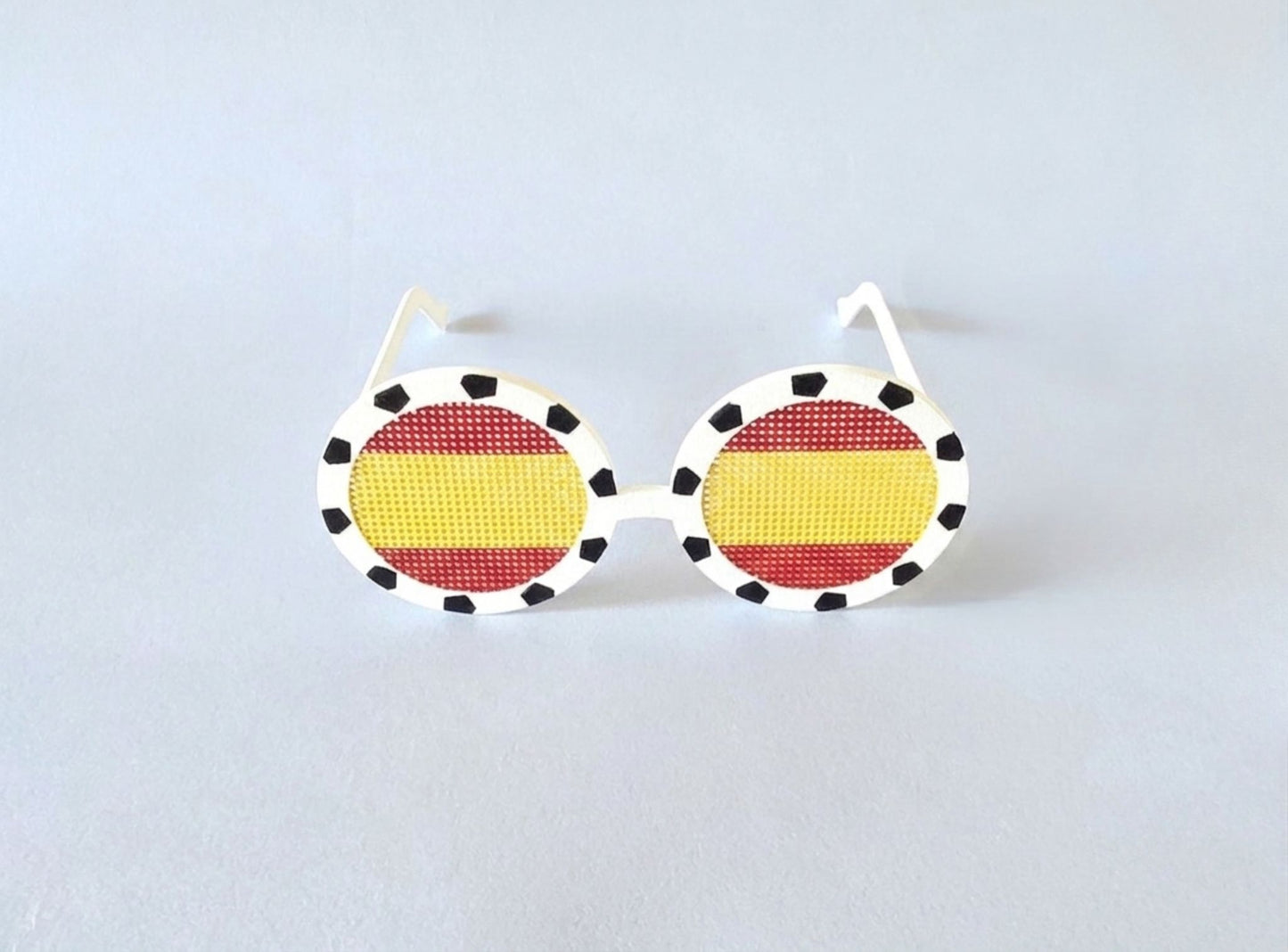 Sunglasses with a Spanish flag design on a light gray background