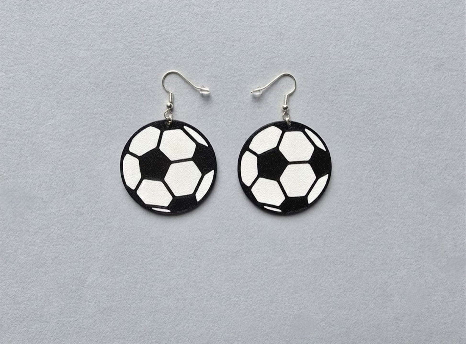 Soccer ball earrings on a gray background