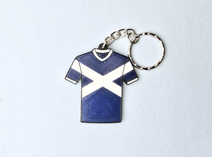 Keychain shaped like a blue and white shirt with a saltire on a light gray background
