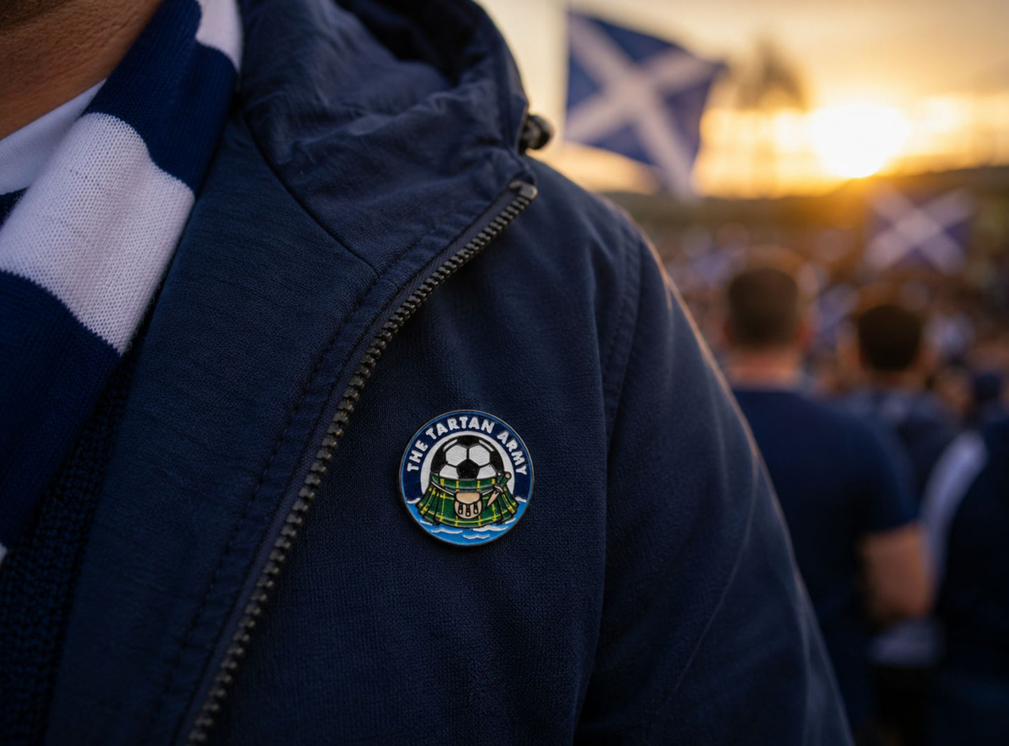 Person wearing a dark blue jacket with a tartan army lapel pin, standing in front of a crowd at an event.